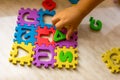 Colorful foam puzzle letters and numbers in kid`s hands on a light table Royalty Free Stock Photo