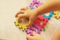 Colorful foam puzzle letters and numbers in kid`s hands on a light table Royalty Free Stock Photo