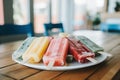 Colorful foggy ice cream, popsicles on plate on wooden table in kitchen, summer, day Royalty Free Stock Photo