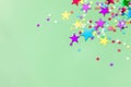 Colorful foil stars confetti sparse on trendy mint colored backg