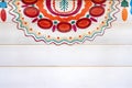 A colorful fragment of the Russian pattern in the style of Dymkovo on wooden wall painted in white