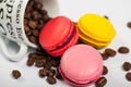 Colorful French delicious macaroons on coffee beans, cup with coffee beans on white background close up Royalty Free Stock Photo