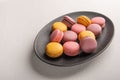 Colorful French or Italian macaron stack on dark plate put on white table with copy space