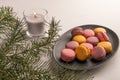 Colorful French or Italian macaron stack on dark plate put on white table. Copy space