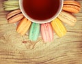 Colorful French Macarons with Cup of Tea on wood background