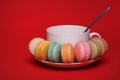 Colorful French Macaroon with Cup of Tea over red