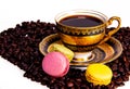 Colorful french macaroons and coffee beans next to cup of cofee