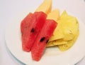 Colorful Fresh fruit including watermelon and pineapple on white dish.