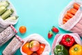 Colorful fresh fruits and vegetables in reusable cotton bags on blue background. Zero waste or responsible food shopping and Royalty Free Stock Photo