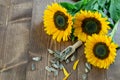 Fresh vivid sunflowers and sunflower seeds on the wooden table, top view