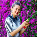 Trendy woman near flowers bed taking photo with smartphone Royalty Free Stock Photo