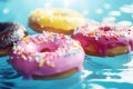 Colorful frosted donuts floating on blue. Concept highlights playful indulgence