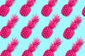 Fruit pattern of neon pink pineapples on a pastel blue background