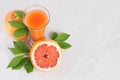 Colorful fruit pink juice with grapefruits and green leaves on white wood board as fresh healthy summer background. Royalty Free Stock Photo