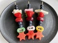 Colorful fruit skewers for children's party on black ceramic plate. Royalty Free Stock Photo