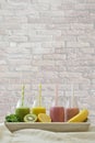 Colorful fruit smoothies in a row with fresh fruits in front of brick wall Royalty Free Stock Photo