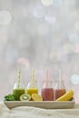 Colorful fruit smoothies in a row with fresh fruits in front of neutral bokeh background Royalty Free Stock Photo