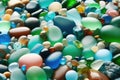 Colorful gemstones on beach. Green, blue shiny glass with multi-colored sea pebbles