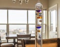 A colorful, glass, liquid filled Galileo Thermometer measures indoor temperature in a room with a view