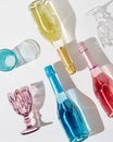 Colorful Glasses for wine and bottle with sparkling wine yellow, pink and blue colors on white table with sunlight Royalty Free Stock Photo