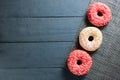 Colorful glazed donuts on dark wooden background.