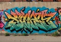 Colorful graffiti art on a concrete wall, featuring bold, angular letters outlined in black. Royalty Free Stock Photo