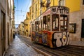 Colorful graffiti-covered trolley parked on a narrow cobblestone street in Lisboa, Portugal Royalty Free Stock Photo