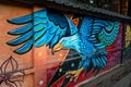 A colorful graffiti of an eagle on a brick wall by an artist