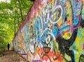 Man walking alongside colorful graffiti at the ruins of Camp Bluefields in Blauvelt State Park, New York