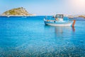 Colorful greek fishing boat at the calm clear water on early summer morning. White rock at the background Royalty Free Stock Photo