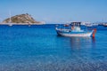 Colorful greek Mediterranean fishing boat at the calm clear blue sea water bay on early summer morning. White rock at Royalty Free Stock Photo