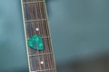 Colorful green guitar pick on finger board