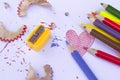 Colorful group of pencil crayons, sharpener and shavings from sharpening on a white paper background. Education frame concept Royalty Free Stock Photo