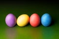 Colorful gypsum easter eggs on green background in a row with reflected color