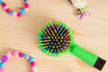 Colorful hair comb crest brushes with handle, bright beads on woden background. Mininmalistic feminine flat lay.