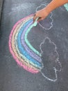 Colorful hand drawn rainbow chalk art on concrete floor. Outdoor family activities, children learning concept