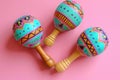 Colorful hand-painted maracas held against a backdrop with vibrant paper confetti