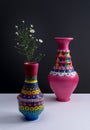 Colorful handcrafted pottery vases and small flowers with harsh shadow Royalty Free Stock Photo