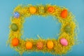 Colorful handmade Easter eggs in a frame made of dry grass. The view from the top. Isolated on a blue background Royalty Free Stock Photo