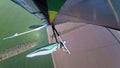 Colorful hangglider wing soars above green cultivated fields