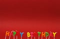 Colorful happy birthday candles on red background