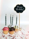 Colorful happy birthday cupcakes with candles with compliments. Birthday cupcake and black board with chalk inscription Royalty Free Stock Photo