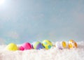 Colorful Happy Easter Eggs in Snow against Blue Sky with sunlight with room or space for copy, text, or your words. Horizontal