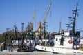 Colorful harbor pier view with small fishing vessels and harbor cranes on blue sky background