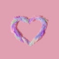 Colorful heart shape made of feathers against pink background. Royalty Free Stock Photo