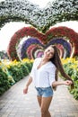 Young woman standing in colorful heart shaped flowers alley in Dubai Miracle Garden