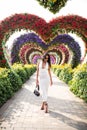 Young woman standing in colorful heart shaped flowers alley in Dubai Miracle Garden