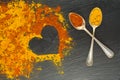 Colorful heart from spices with two vintage spoons on black background with two vintage spoons. Selective focus. Valentines day. Royalty Free Stock Photo