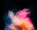 Colorful holi powder blowing up on black background.