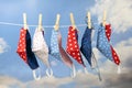 Colorful homemade community face masks for protection from coronavirus pandemic are hanging on a clothesline against a blue sky